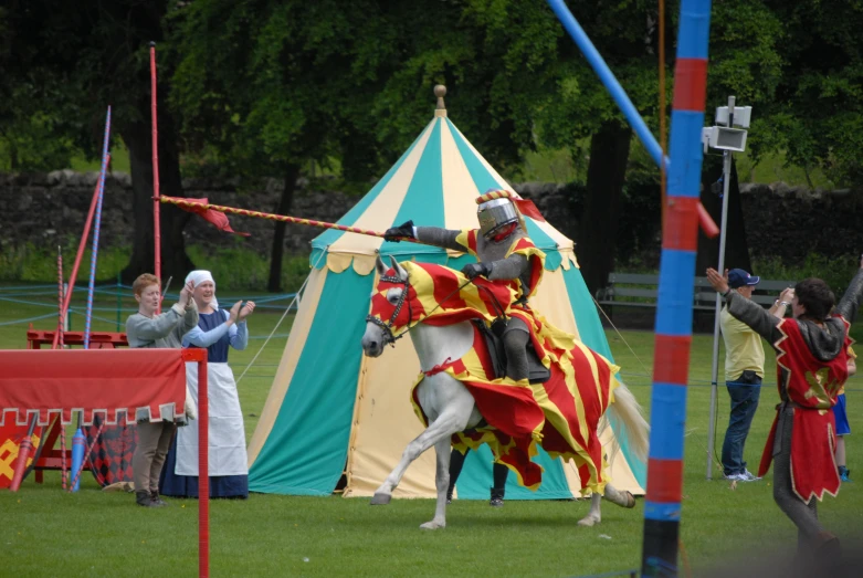 a man dressed in renaissance style armor riding a horse with people watching