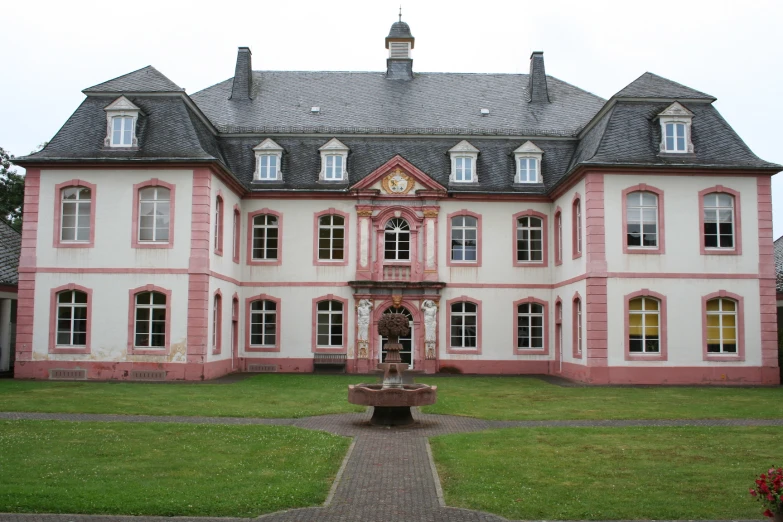 an old, large pink and white building with a fountain in front