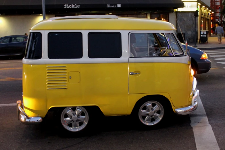 a yellow van parked in the street with two people in it