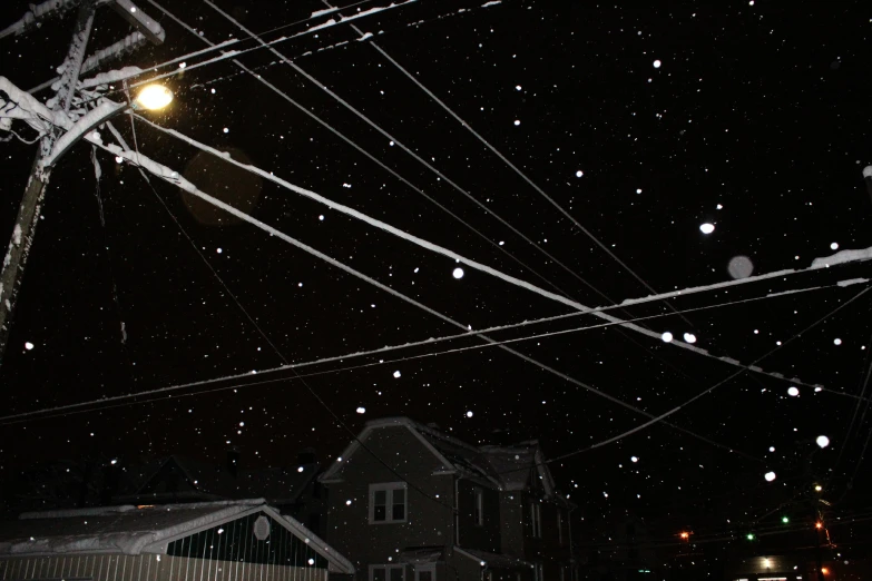 the view up a hill with power lines covered in snow and the light pole above it