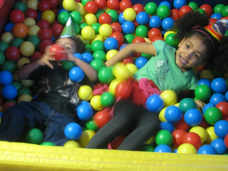 two s play in a ball pit with one child reaching for a toy