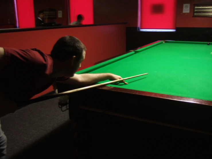 a man standing at a pool table holding a cue in his hand