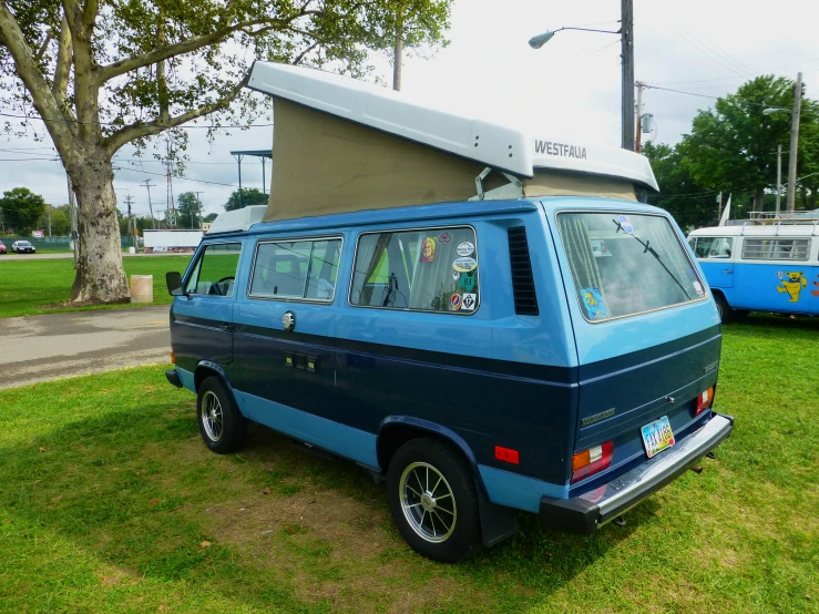 an old blue van parked in the grass by a building