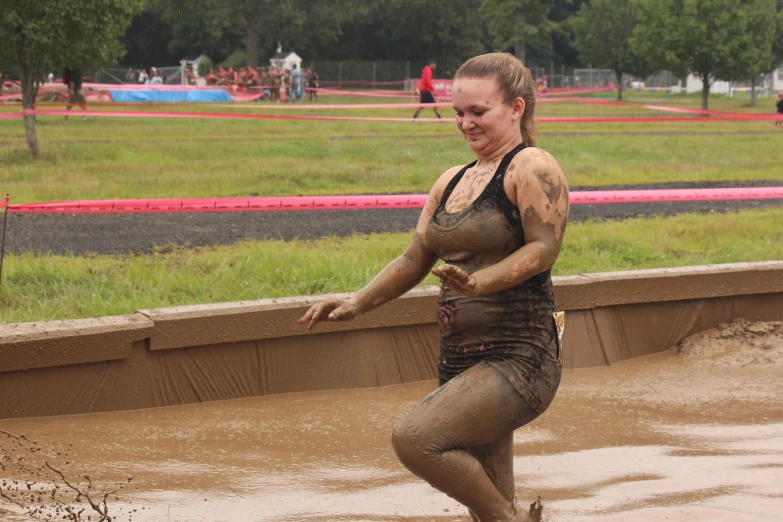 a woman with mud on her body standing in a flooded area