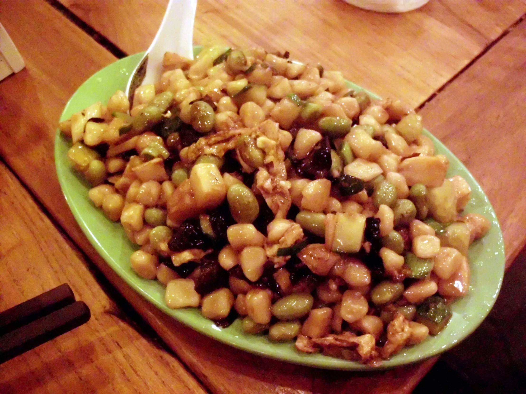 a green plate with food and fork on wooden table