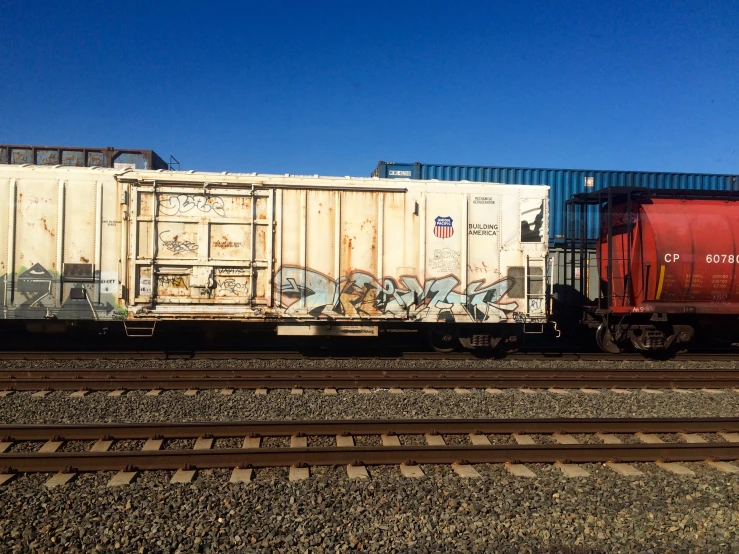 a train with a red trailer sitting on some tracks