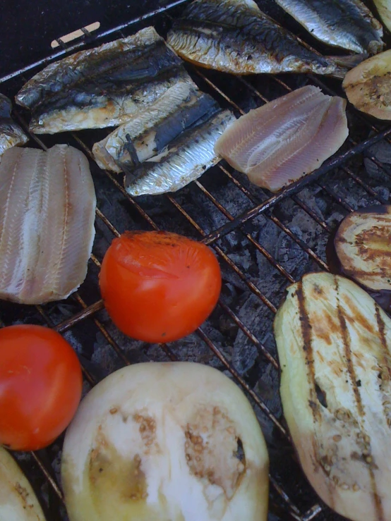 some fish and other foods cooking on an outdoor grill