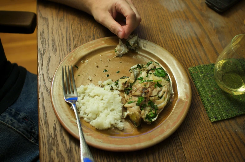 someone with their fingers on their plate and a fork in their hand