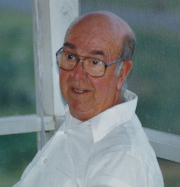 a man in white shirt and glasses next to a window