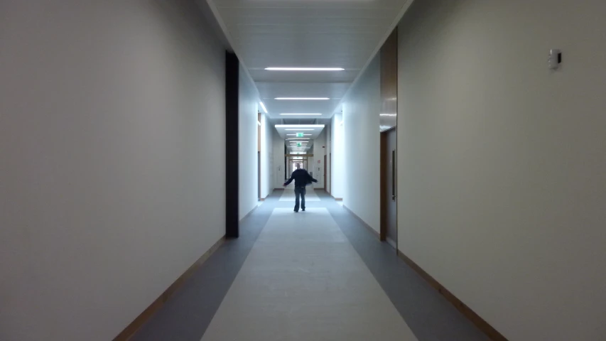 a man walks down a white hallway