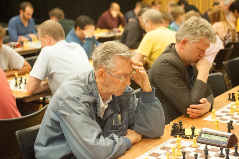 several people sitting at tables with chess on the tables