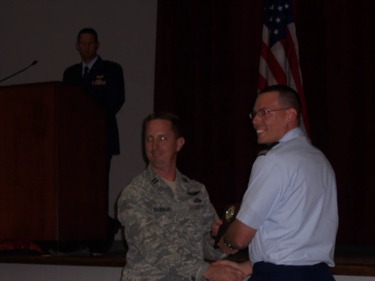 a couple of guys giving an award to a man