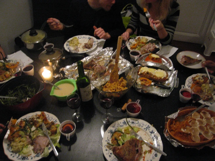 many people gathered around a table covered in plates