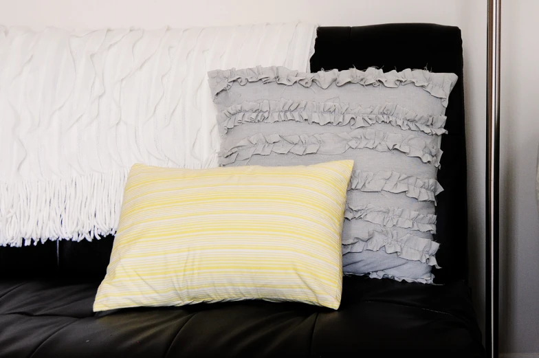 four pillows on a black couch are featured