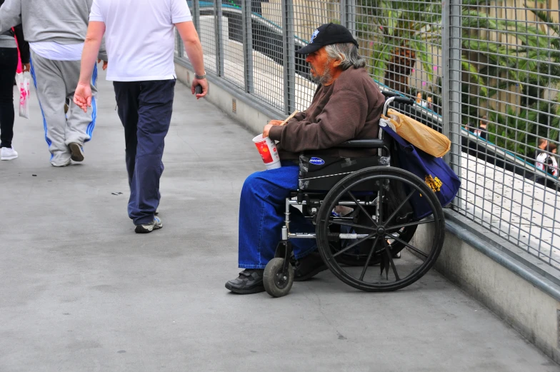 an older person in a wheel chair in front of a metal fence