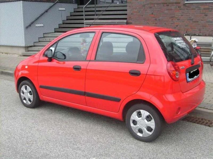 an orange small car is parked in front of a building