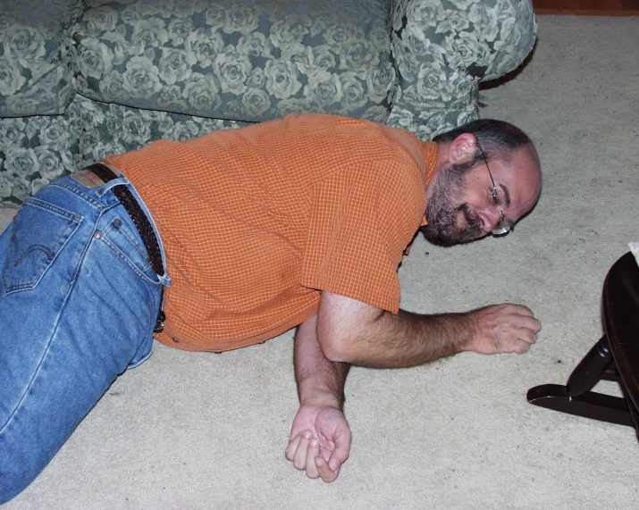 a man is sleeping on the floor near his couch
