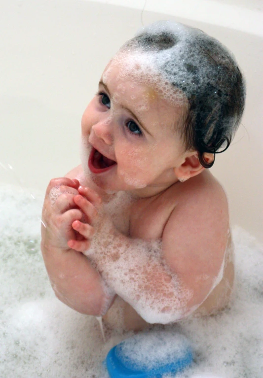 a baby sitting in the bathtub with foam all over it