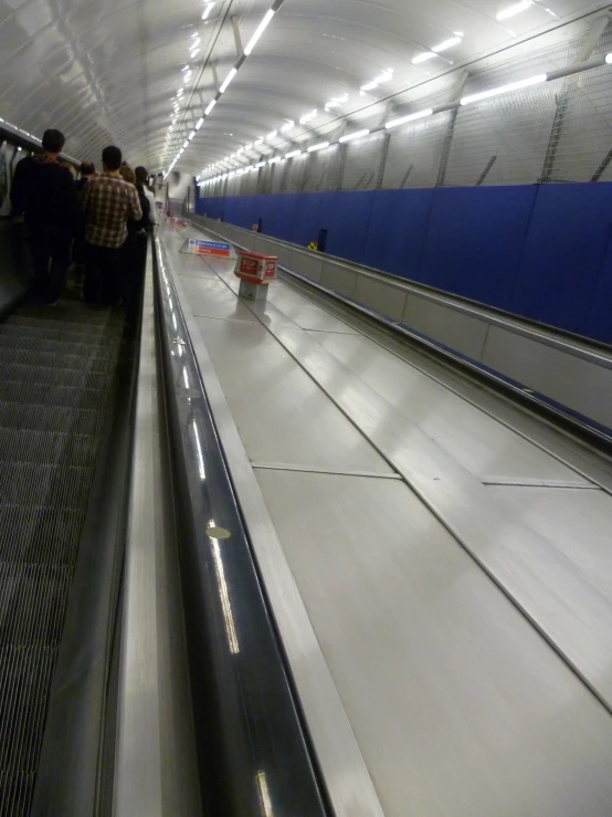 people are waiting on an escalator in a building