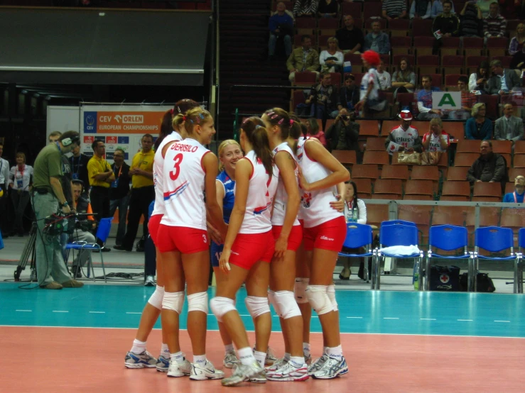three women in white and red uniforms playing volleyball