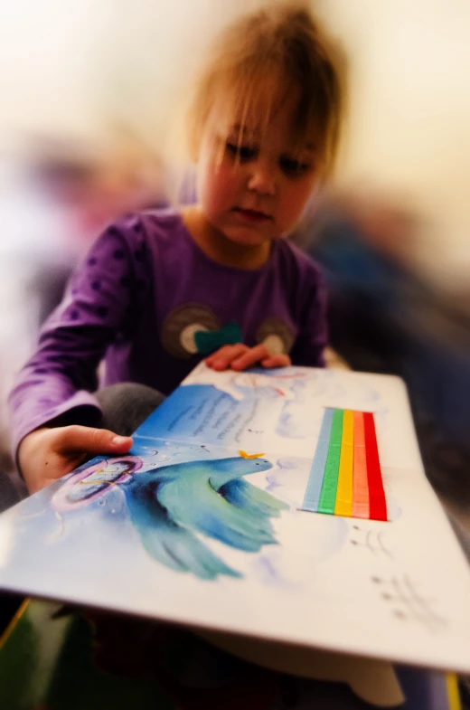  holding drawing paper with the image of rainbow on it