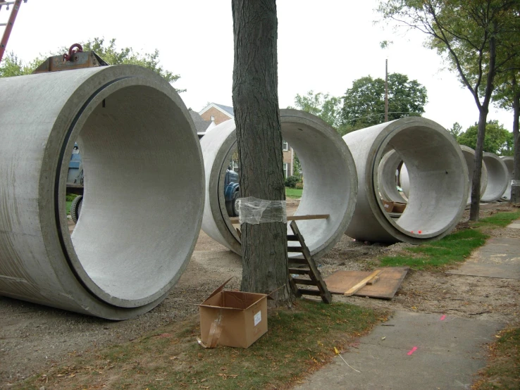 several grey tubes sitting next to a tree on a sidewalk