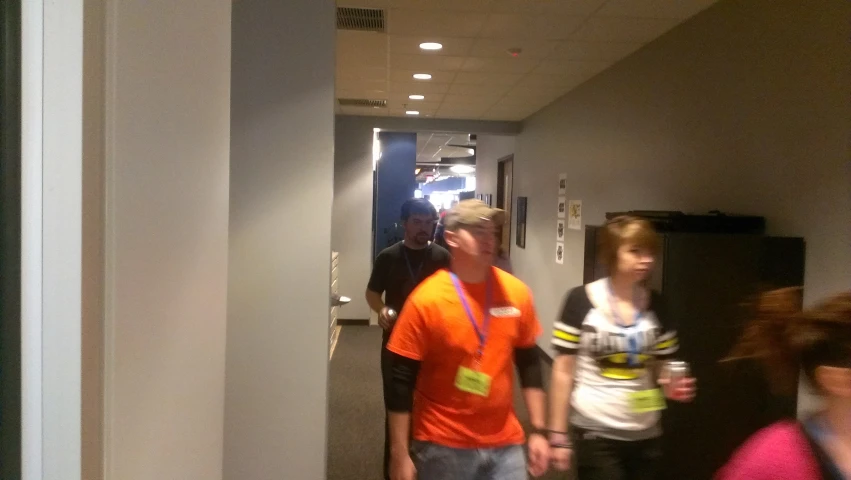 a man and woman walk down a hallway while talking