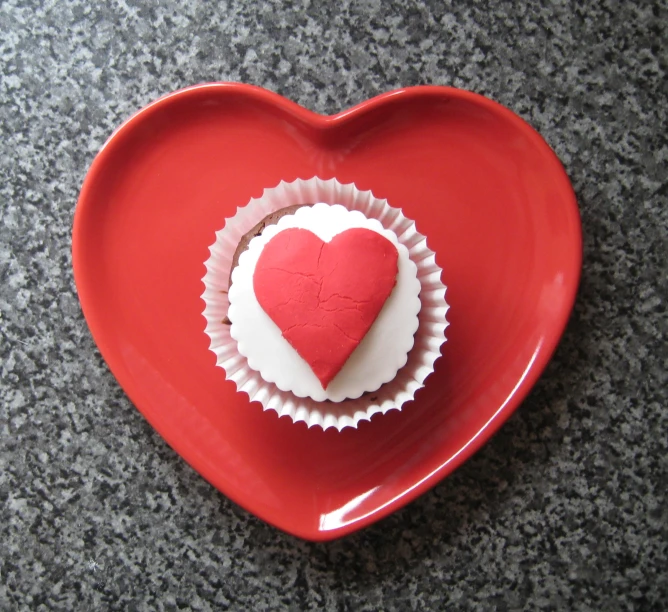 a plate shaped like a heart with a cupcake on it