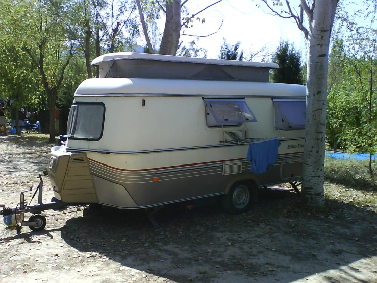 an old style camper is parked under a tree