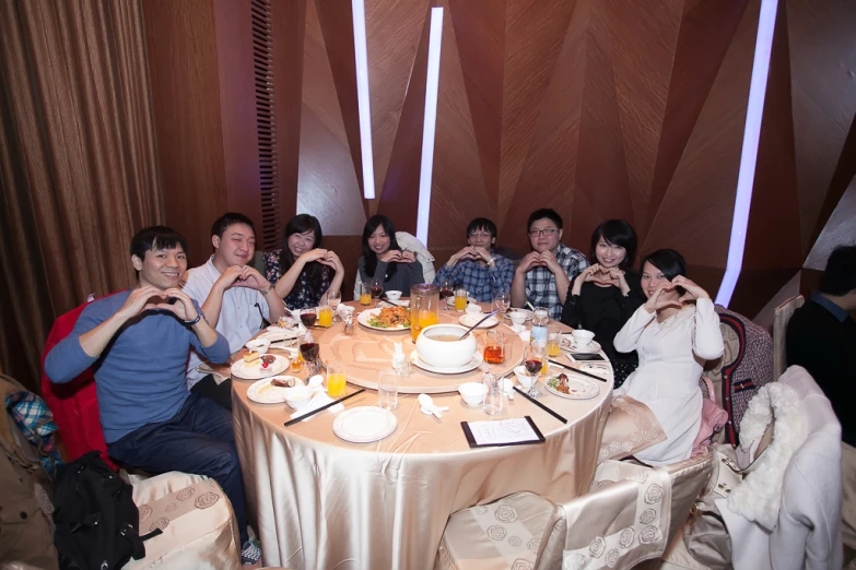 a large group of people seated around a table posing for the camera