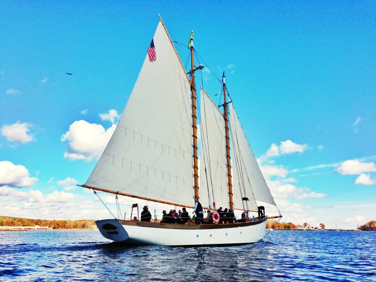 an old sailboat with white sails floating in the ocean