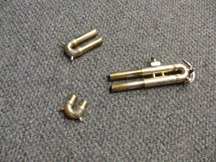 three metal handles and two silver clips lying on a gray carpet
