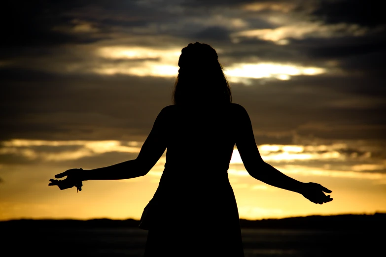 a woman with long hair and a star in her hand standing in front of the sun