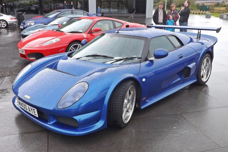 three very pretty cars are parked in the rain