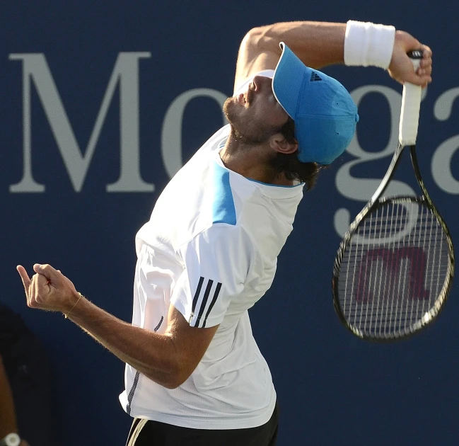 a male tennis player in a blue hat hits the ball