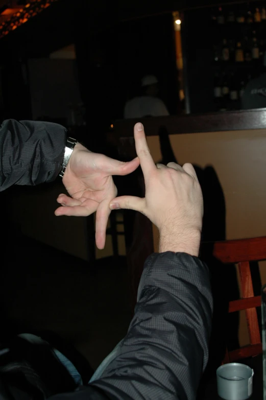 two hands making a sign over a cup