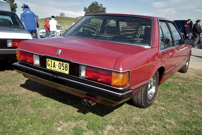 a red station wagon is sitting outside near others in the distance