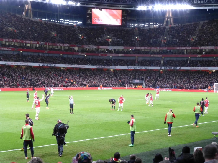 a soccer field with a group of people standing around it