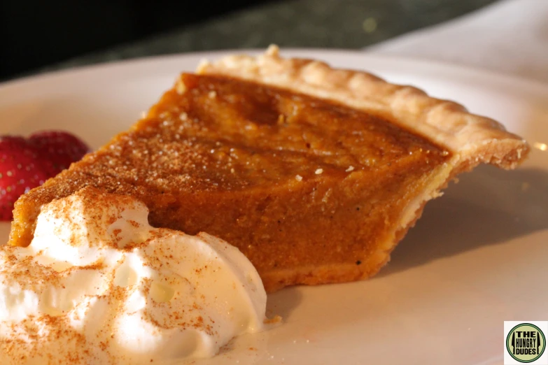 a piece of pie on a plate with ice cream and strawberry