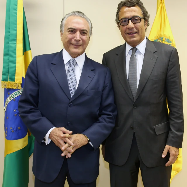 two businessmen standing near each other in front of flags