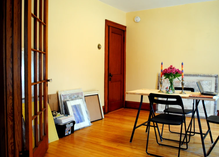 an empty room with a wooden table and chairs and pictures on the floor