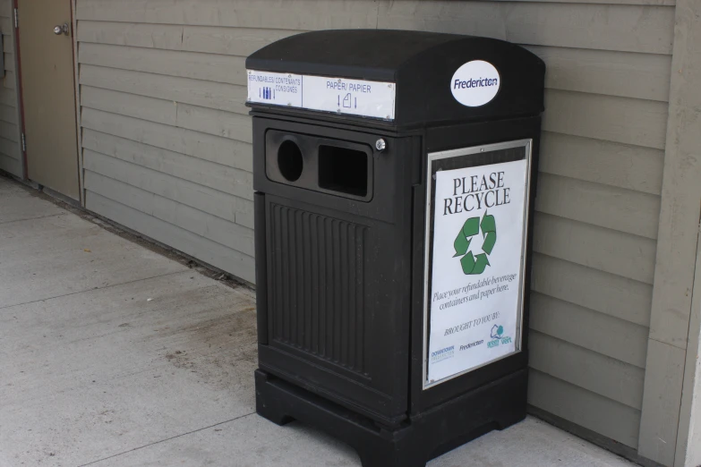 a black litter box is outside on the sidewalk