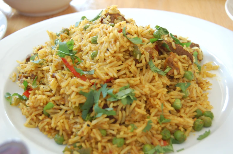 a plate filled with rice, peas and cilantro on a table