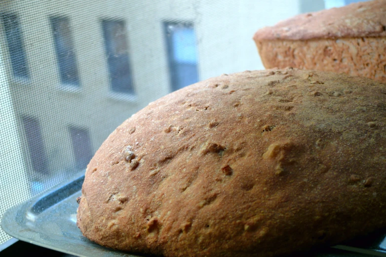 the two breads are on the pan in front of the window