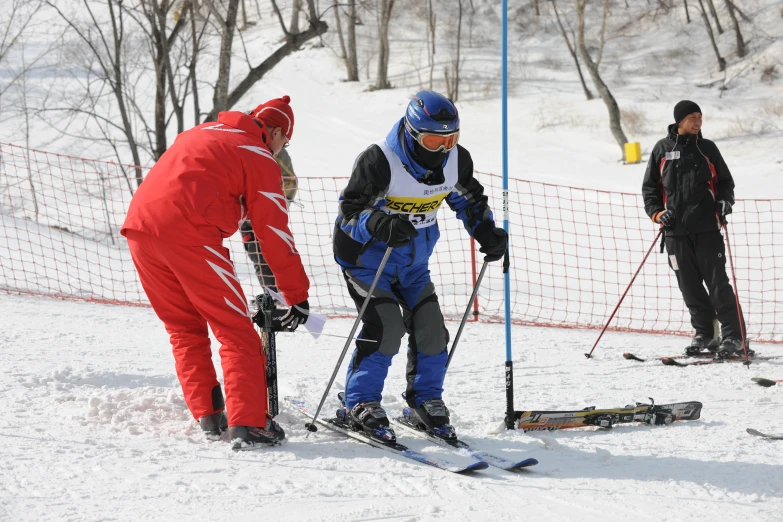 two men wearing skis standing in the snow next to a net