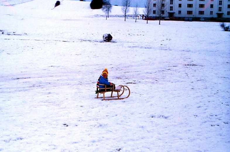 a little girl sitting on a sled that is in the snow