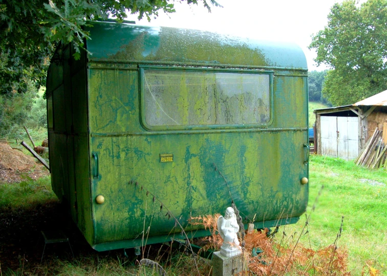 an old green trailer is sitting in a field