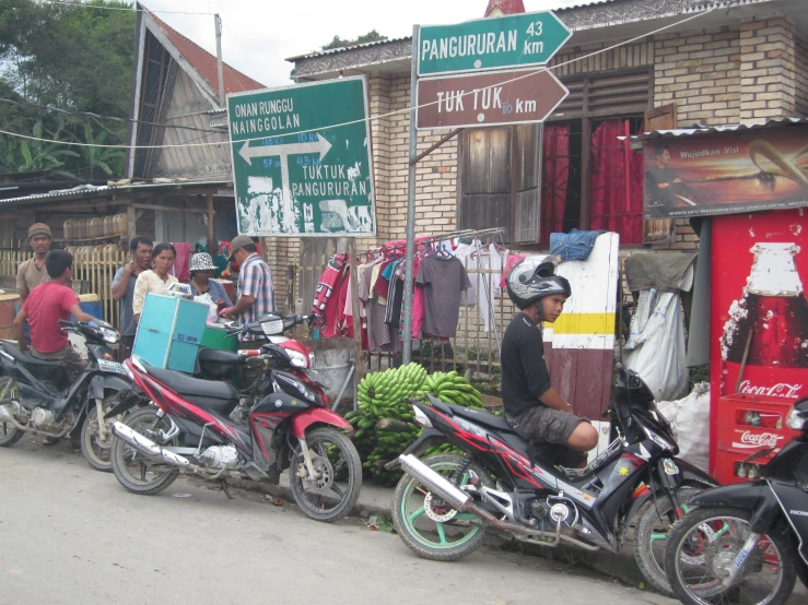 a few people riding motorcycles near a bunch of other motorcycles