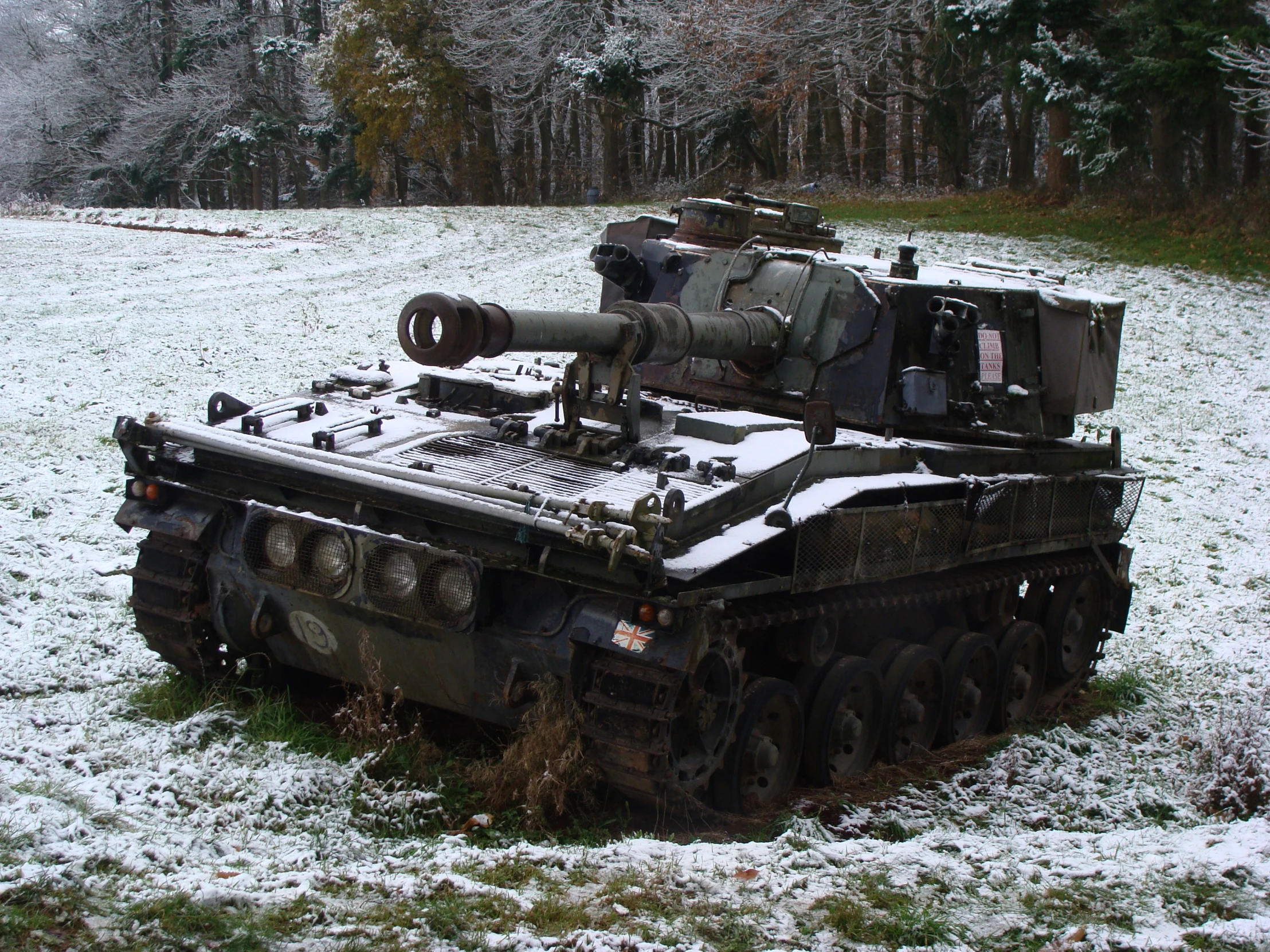 a tank sitting in the snow and a person standing on top