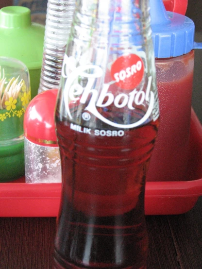 a bottle of soda sitting on a tray next to plastic cups